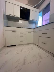 a kitchen with white cabinets and a microwave at Metro Nook in Lucknow