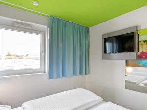 Schlafzimmer mit einem Bett und einem Fenster mit einem TV in der Unterkunft B&B Hotel Hamburg-Wandsbek in Hamburg