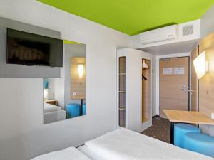 Cette chambre comprend un lit, une table et une télévision. dans l'établissement B&B Hotel Hamburg-Wandsbek, à Hambourg