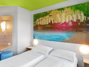- une chambre avec un lit et une peinture murale dans l'établissement B&B Hotel Hamburg-Wandsbek, à Hambourg