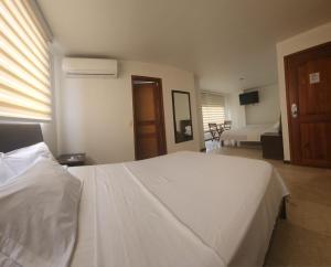 a bedroom with a large white bed and a window at Hotel Ciudad Capri in Cali