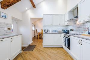 a kitchen with white cabinets and a wooden floor at Stunning 3-bed cottage in Beeston by 53 Degrees Property, ideal for Families & Groups, Great Location - Sleeps 6 in Beeston