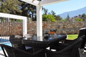 een tafel en stoelen op een patio met een stenen muur bij Hisar Prestige D in Fethiye