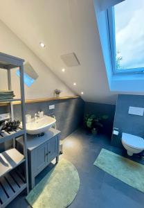ein Bad mit einem Waschbecken, einem WC und einem Fenster in der Unterkunft Liebling's Platzl in Eberfing