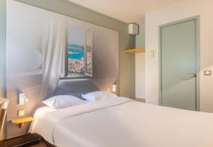 Un dormitorio con una cama blanca y una ventana. en B&B HOTEL Toulon La Seyne sur Mer, en La Seyne-sur-Mer