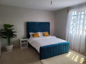 a bedroom with a large bed with a blue headboard at Wike Suites in Nakuru
