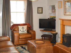 uma sala de estar com uma cadeira e uma televisão em Wilsons em Golspie