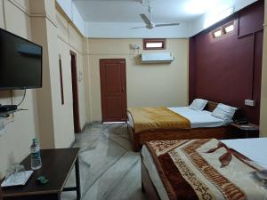 a hotel room with two beds and a flat screen tv at Hotel Yuvraj Palace in Chutiyā Mīrigaon
