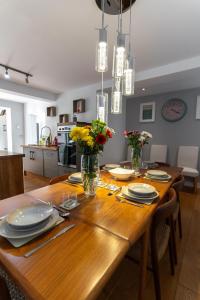 a wooden dining room table with plates and flowers on it at Executive High-End Luxury Accommodation in Southampton, Perfect for Relocators, Contractors and Professionals in Southampton