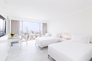 a white hotel room with two beds and a window at Pullman Bangkok Hotel G in Bangkok