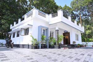 a white house with a motorcycle parked in front of it at Holiday Villa - Your Second Home - Kothamangalam in Kotamangalam