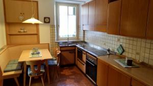 uma cozinha com armários de madeira, uma pequena mesa e uma janela em Casa Micéi em Tesero