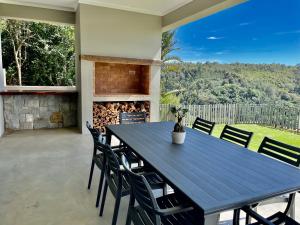 una mesa azul y sillas en un patio con chimenea en Hilltop 39 House, Oubaai Golf Estate, en Herolds Bay