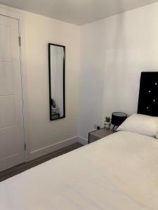 1 dormitorio con cama blanca y espejo en One Bedroom Apartment in Luton Town Centre, en Luton