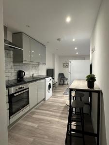 a kitchen with white cabinets and a table and a counter at One Bedroom Apartment in Luton Town Centre in Luton