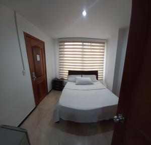 a bedroom with a large bed and a window at Hotel Ciudad Capri in Cali