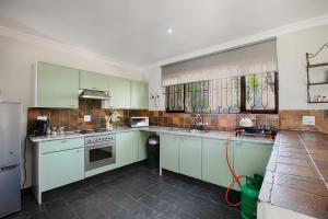 a kitchen with green and white cabinets and a refrigerator at The River Cottage in Muldersdrift
