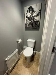 a bathroom with a toilet and a picture of a man reading at The Bainden , With Private Secluded Hot Tub in Rotherfield