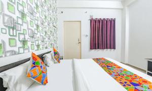 a bedroom with a white bed with colorful pillows at FabExpress Ashiyana Inn in Patna