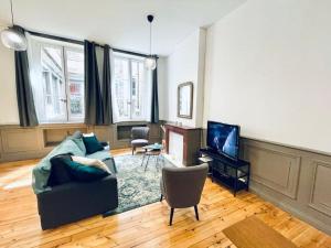 een woonkamer met een bank en een televisie bij Le Bernou : Hypercentre- calme et unique! in Saint-Étienne