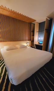 duże białe łóżko w pokoju hotelowym w obiekcie Hotel Joinville Hippodrome w mieście Joinville-le-Pont