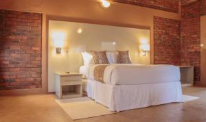 a bedroom with a white bed and a brick wall at Deluxe room on a resort - 2182 in Kingsmead