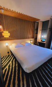 Hotel Joinville Hippodrome في جوافيل: سرير أبيض كبير في غرفة الفندق