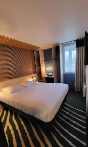 Hotel Joinville Hippodrome في جوافيل: سرير كبير في غرفة الفندق مع نافذة