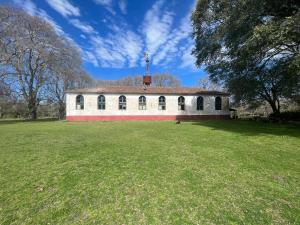 ein großes Gebäude mit einem Grasfeld davor in der Unterkunft Estancia Santa Rita in Punta Indio