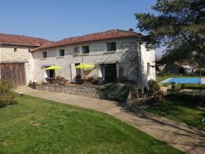a stone house with umbrellas and a swimming pool at Les Granges de la Leigne, Ruffec in Condac