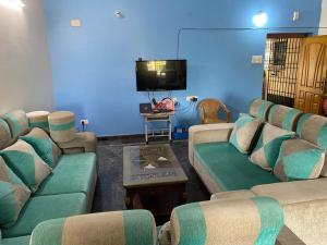 a living room with couches and a flat screen tv at NETHRA ILLAM in Chennai