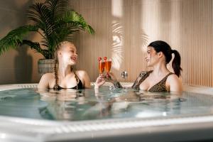 Duas raparigas numa banheira a segurar taças de champanhe. em Hotelli Lähde em Lappeenranta