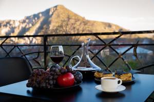 a table with a glass of wine and a plate of fruit at BMG Hotel by Grigoryans Group in Goris