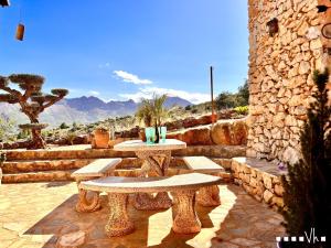 un patio con 2 mesas de picnic y una pared de piedra en VH CostaBlanca - CALIMA, en Benissa