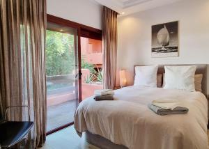 ein Schlafzimmer mit einem großen Bett und einer Glasschiebetür in der Unterkunft Luxury Apartment in Jardines De Don Carlos in Marbella