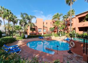einen Pool in einem Resort mit Stühlen und Palmen in der Unterkunft Luxury Apartment in Jardines De Don Carlos in Marbella