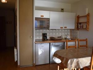 uma cozinha com armários brancos e uma mesa num quarto em Appartement Font-Romeu-Odeillo-Via, 2 pièces, 6 personnes - FR-1-580-19 em Font Romeu Odeillo Via