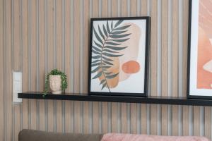 a shelf on a wall with a picture and a plant at Elegant Apartment for 4 with Parking in Poznan by Renters in Poznań