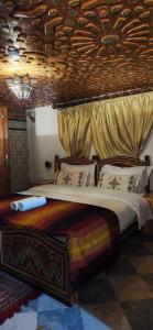a bedroom with a large bed with a wooden ceiling at Riad Royal in Meknès