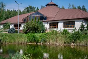 a house with a pond in front of it at Resto Park Традиція in Podvorki