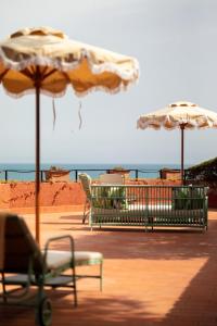 twee stoelen en parasols op een strand met de oceaan bij Il Pellicano in Porto Ercole