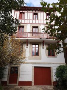 a building with red doors and a balcony at Saint-Jean de Luz, appartement vue mer 4 couchages in St. Jean de Luz