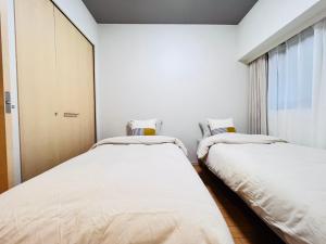 twee bedden in een kamer met witte muren bij Jun KBK- 606 in Tokyo