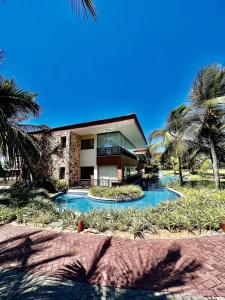 a house with a swimming pool and palm trees at Mandara Lanai Apartamento Bangalô in Aquiraz