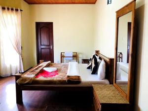 een slaapkamer met een groot bed en een spiegel bij Shevyhaws in Nuwara Eliya