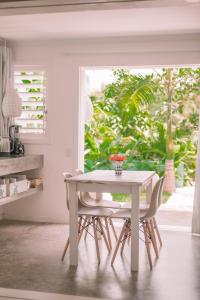 uma mesa branca e cadeiras num quarto com uma janela em Cactus Lodge Pipa em Pipa