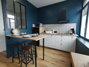 a kitchen with blue walls and a table with stools at Résidence Beaudelot in Saint-Saulve