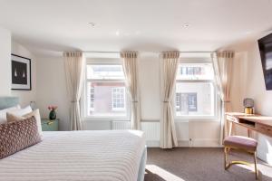 een slaapkamer met een wit bed en 2 ramen bij 2 Bedroom Apartments in Covent Garden in Londen