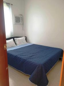 een slaapkamer met een bed met een blauwe sprei bij Villa Susane in Balamban