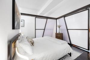 a bedroom with a white bed and windows at Streetcar Serenity Condo in New Orleans